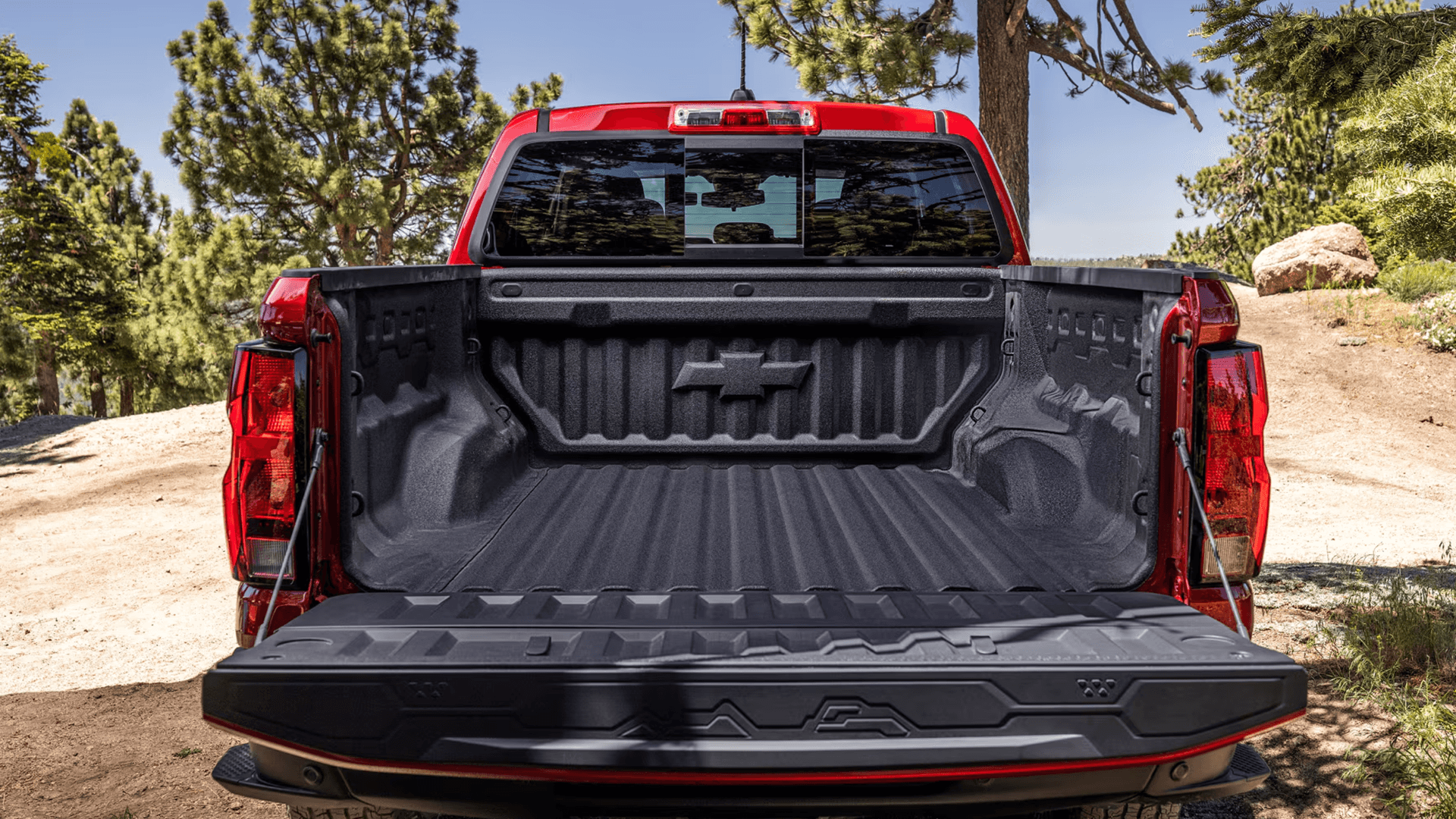Open Chevy Colorado truck bed with tailgate down showing tie-downs and cargo