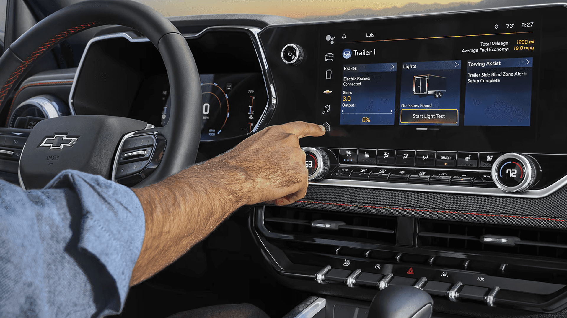 Driver using the Chevy Colorado infotainment screen to adjust trailer brakes, lights, and towing assist settings