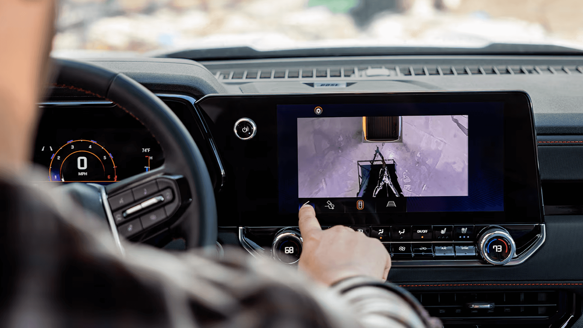 Driver using the Chevy Colorado infotainment screen to view a rear trailering camera