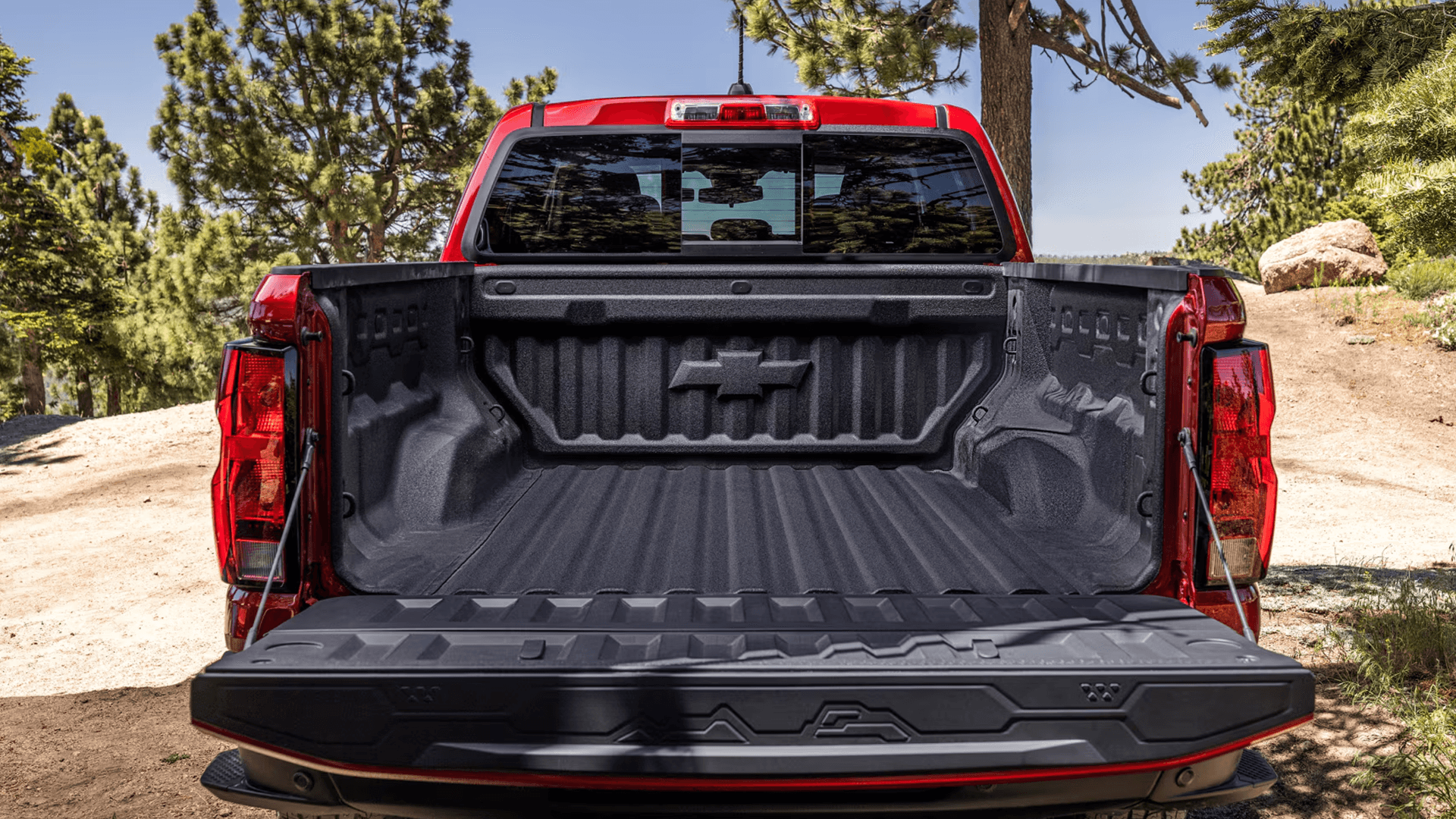 Open truck bed of a red Chevy Colorado with spray in bedliner and tailgate down