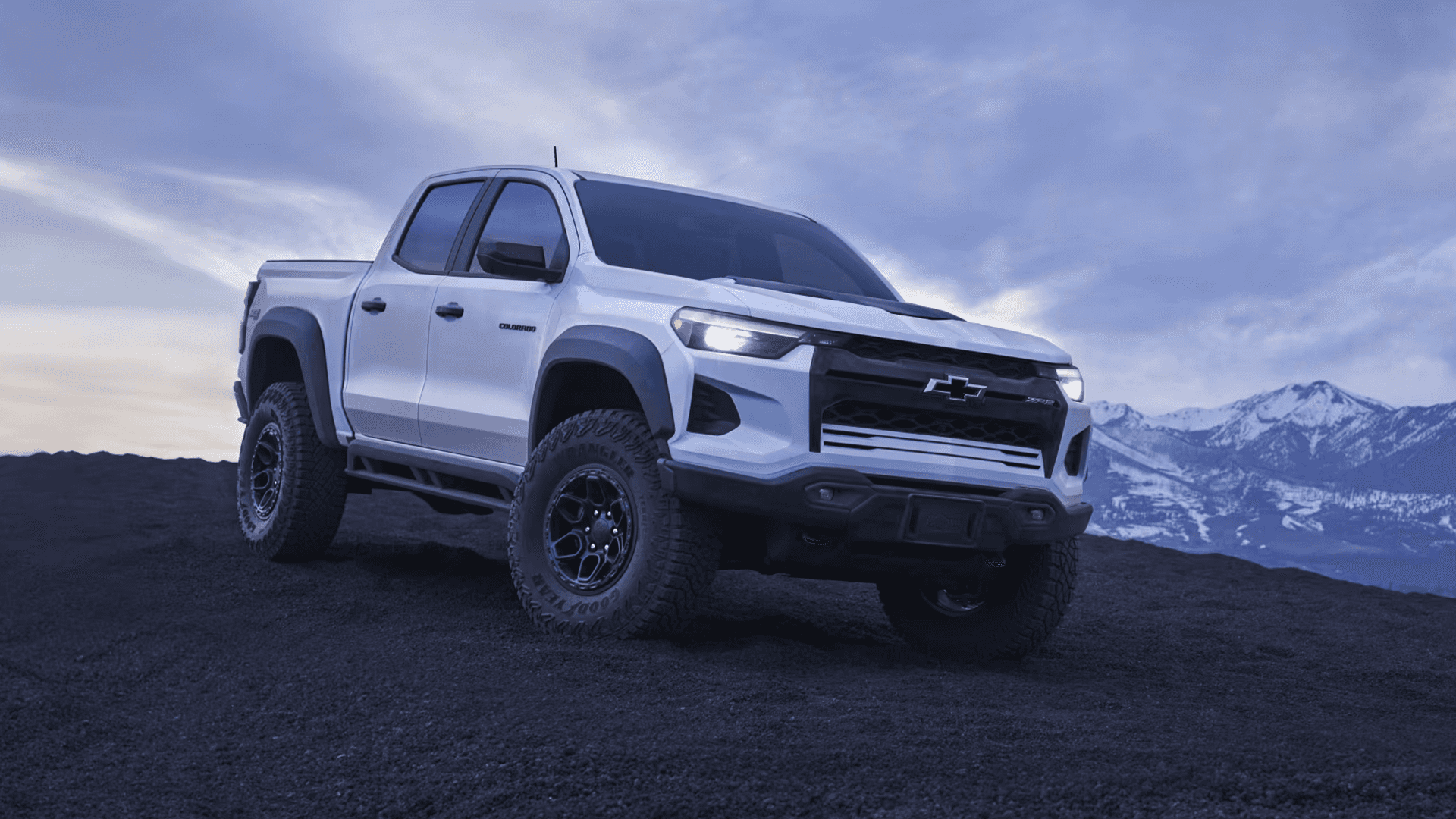 White Chevy Colorado ZR2 parked on rocky terrain with mountain backdrop