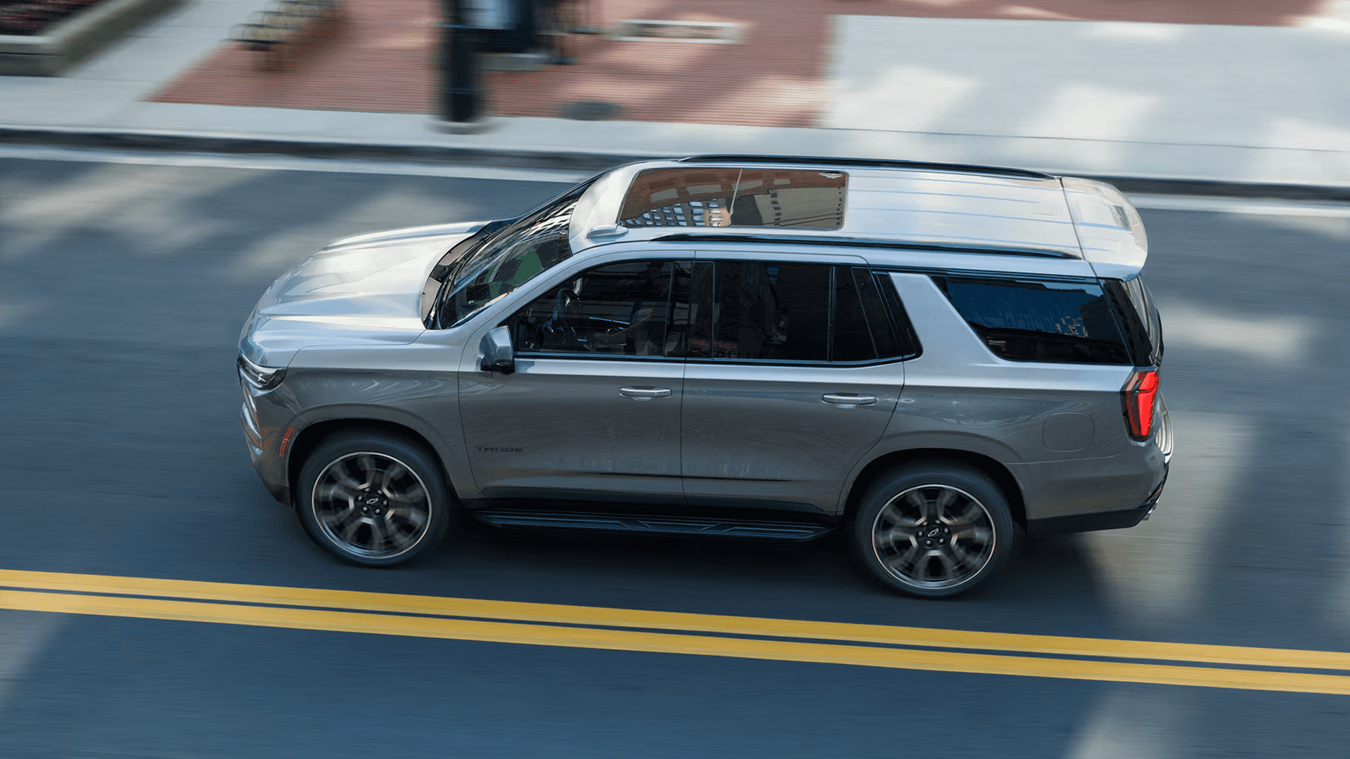 Overhead side view of a 2026 Chevy Tahoe driving on a city street