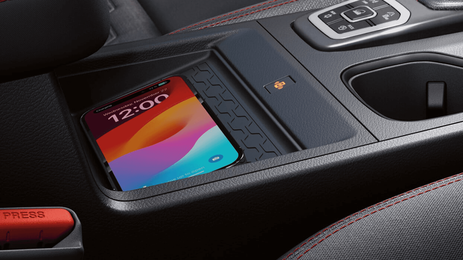 Smartphone resting on an in cabin wireless charging pad next to front cupholders