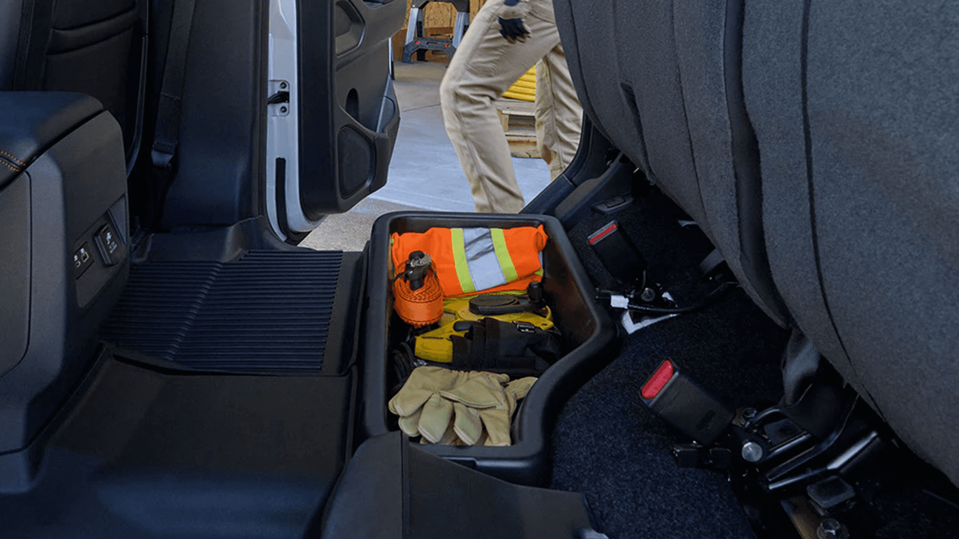 Under seat rear storage bin holding work gear behind the front seats