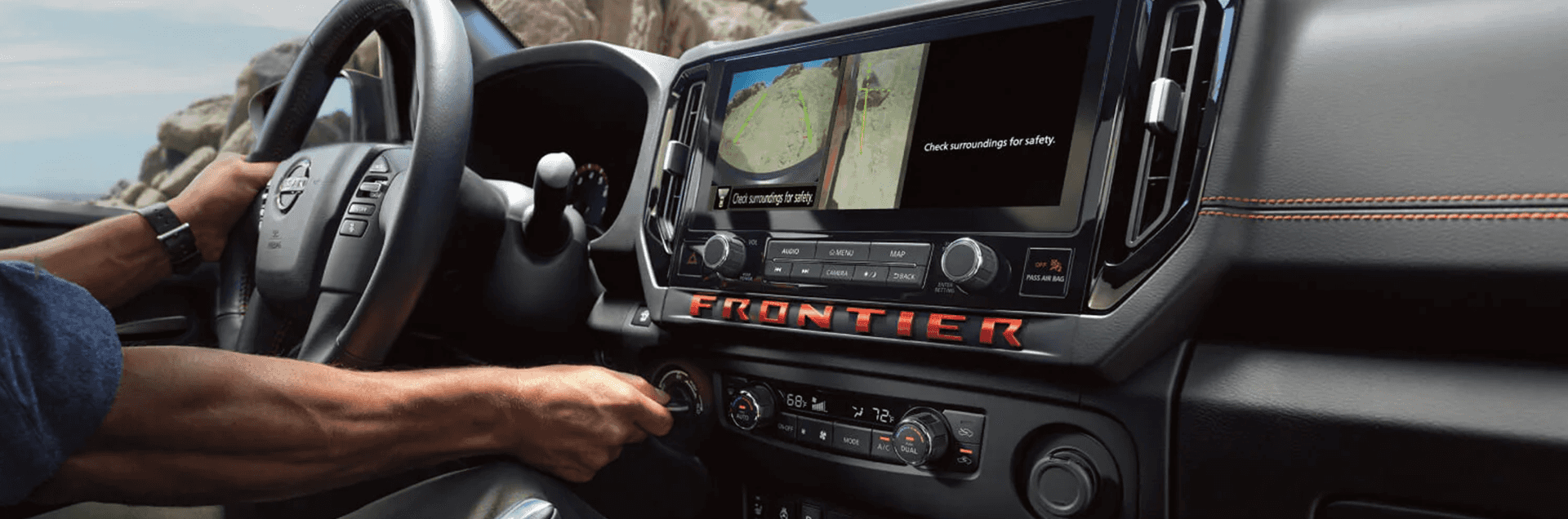 Driver using the Nissan Frontier center display with camera views on screen