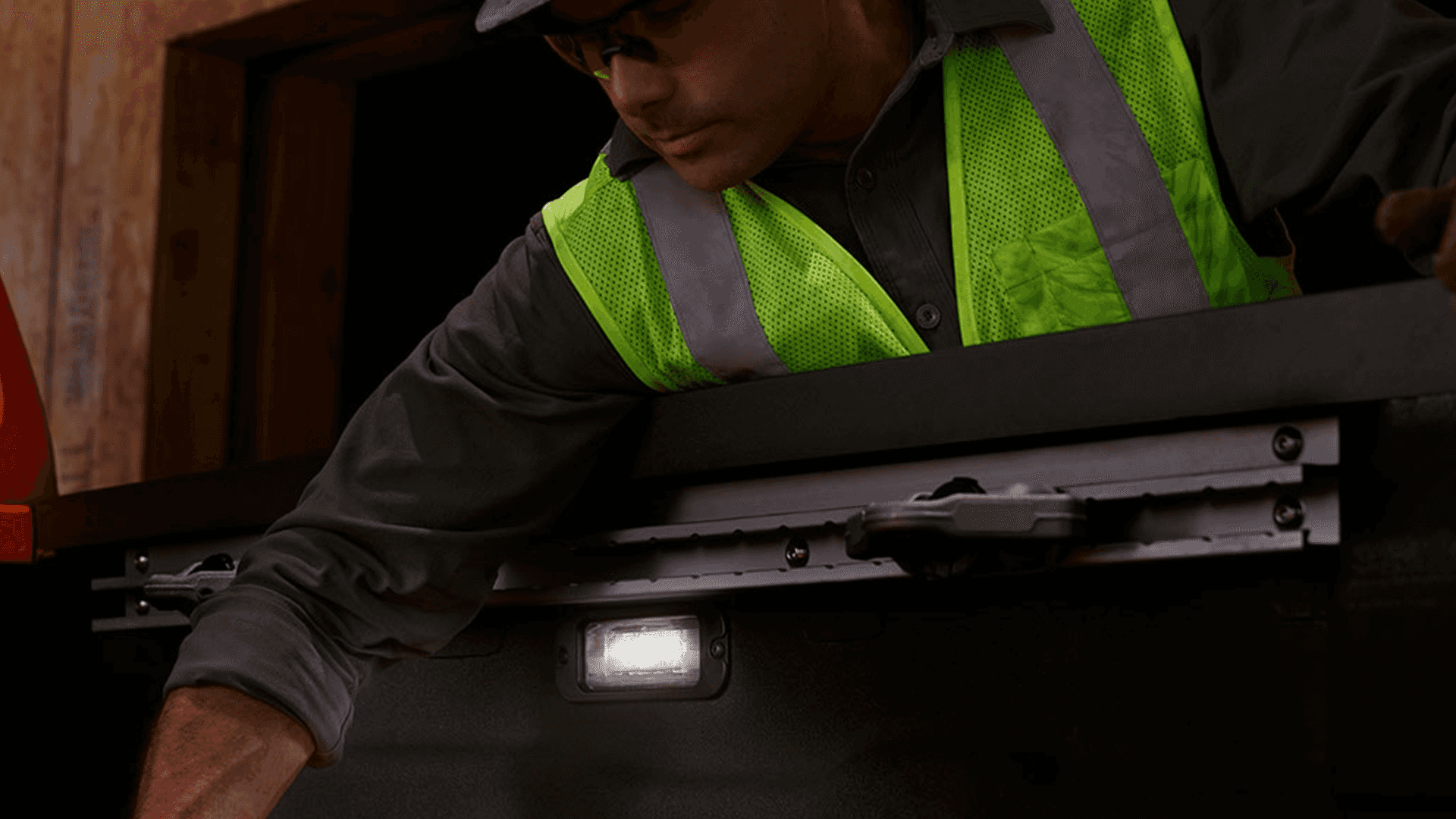 Worker reaching into a Nissan Frontier truck bed with bed lighting on