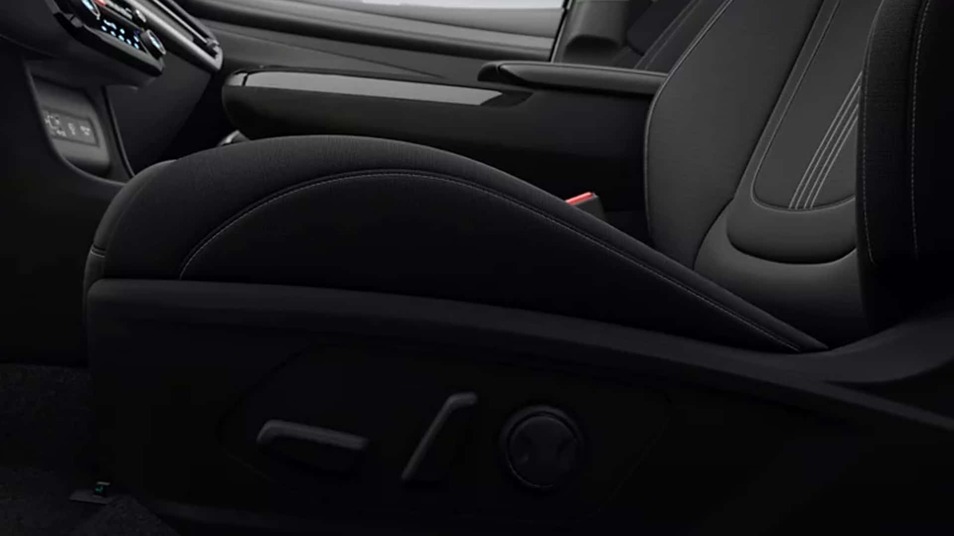 Close-up of Hyundai Tucson Hybrid front seat upholstery and power seat controls, highlighting comfort-focused interior design.