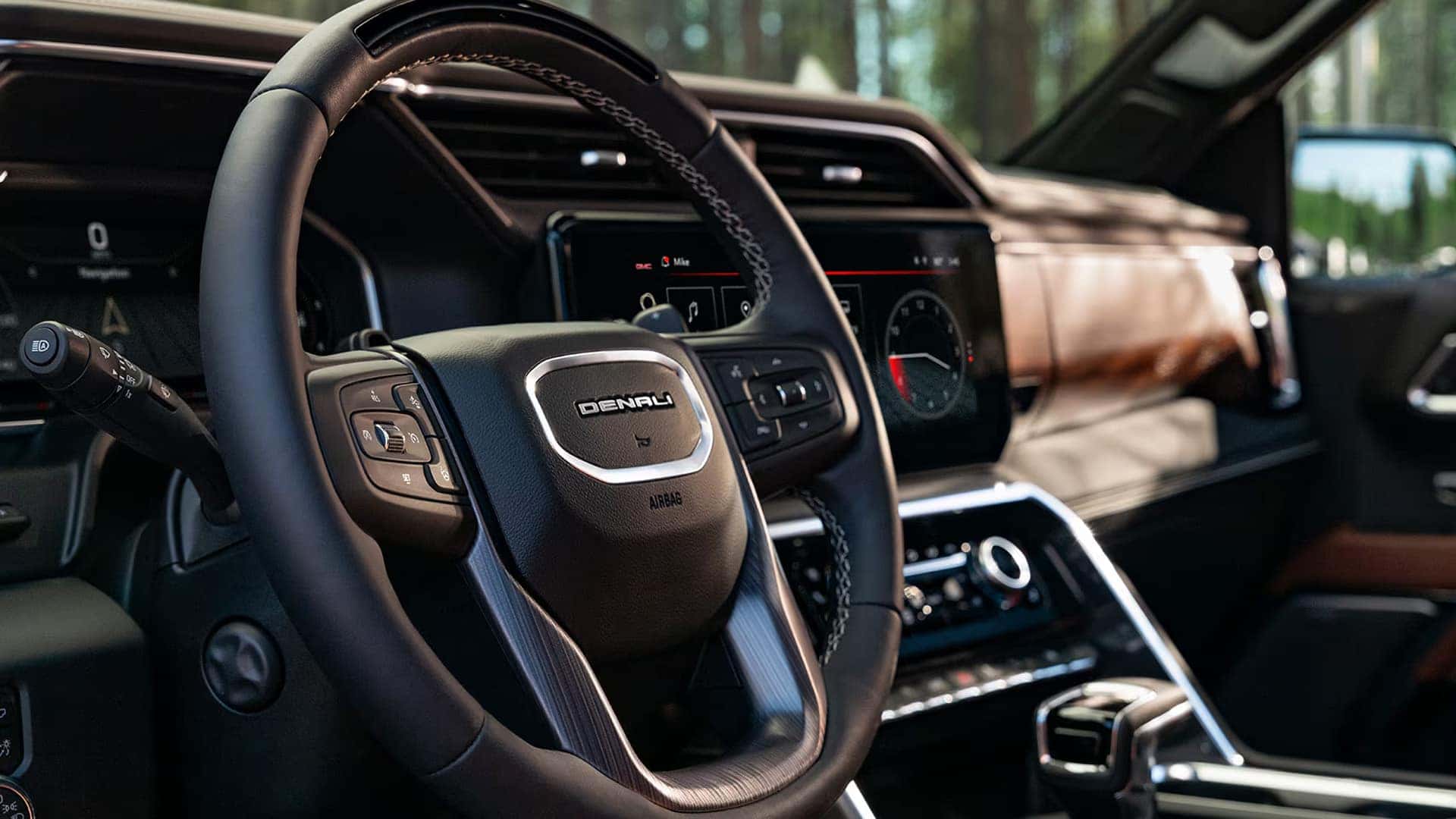 GMC Sierra 1500 Denali interior showing leather-wrapped steering wheel, digital driver display, and large center touchscreen.