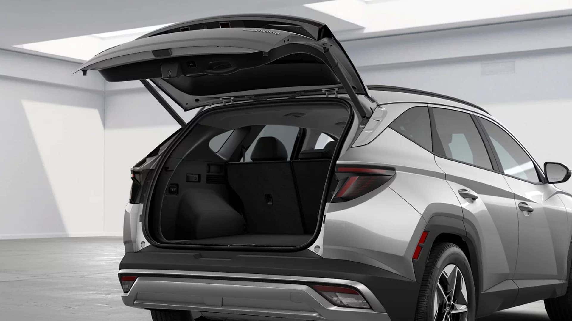 Rear view of a Hyundai Tucson Hybrid with the liftgate open, showing spacious cargo area and flexible storage capacity.