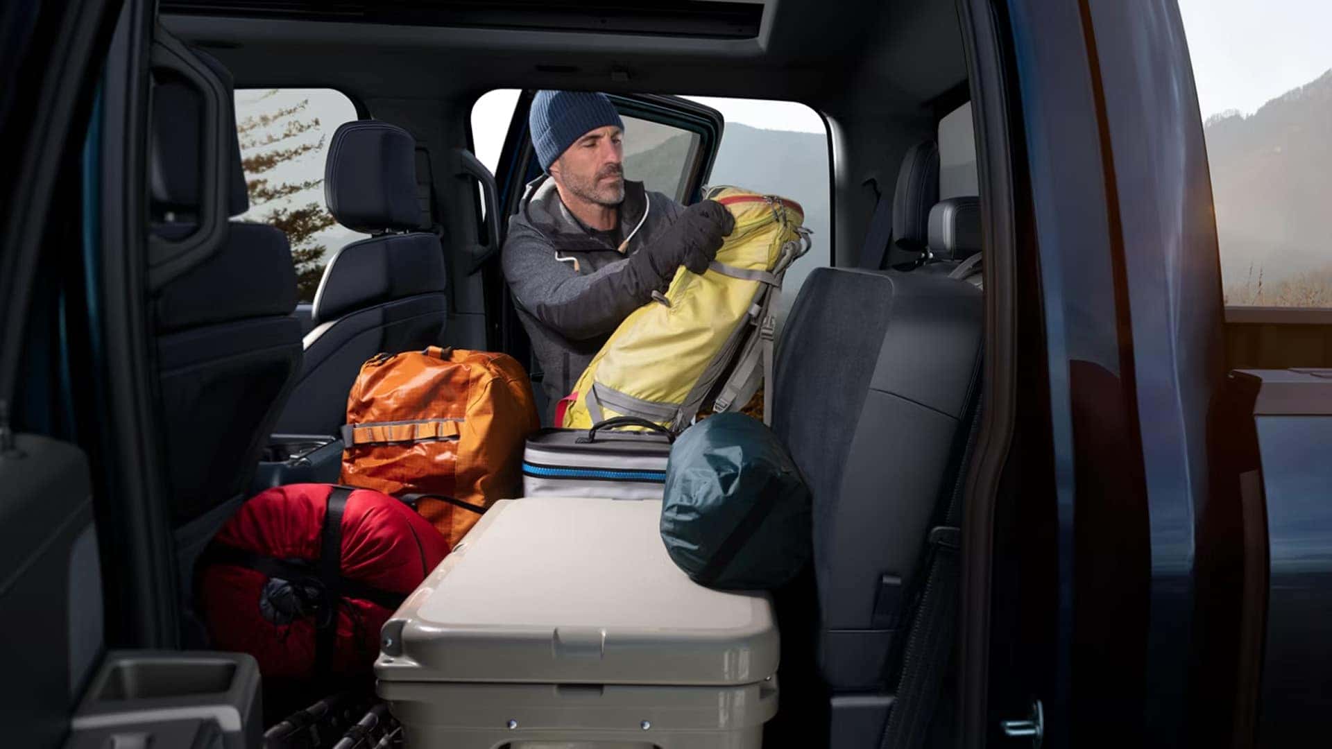 2026 Ford F-150 rear cabin storage with folded seating area loaded with camping gear and equipment for travel