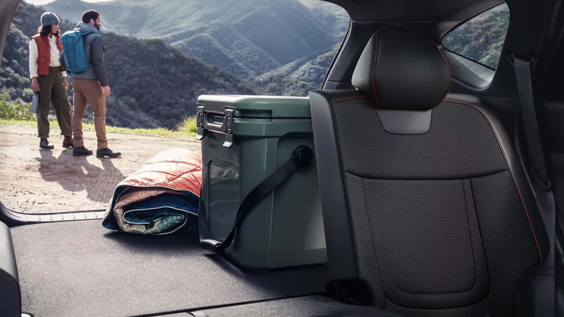 Rear cargo area of the Hyundai Tucson Hybrid with storage bins and gear loaded, demonstrating flexible interior cargo space.