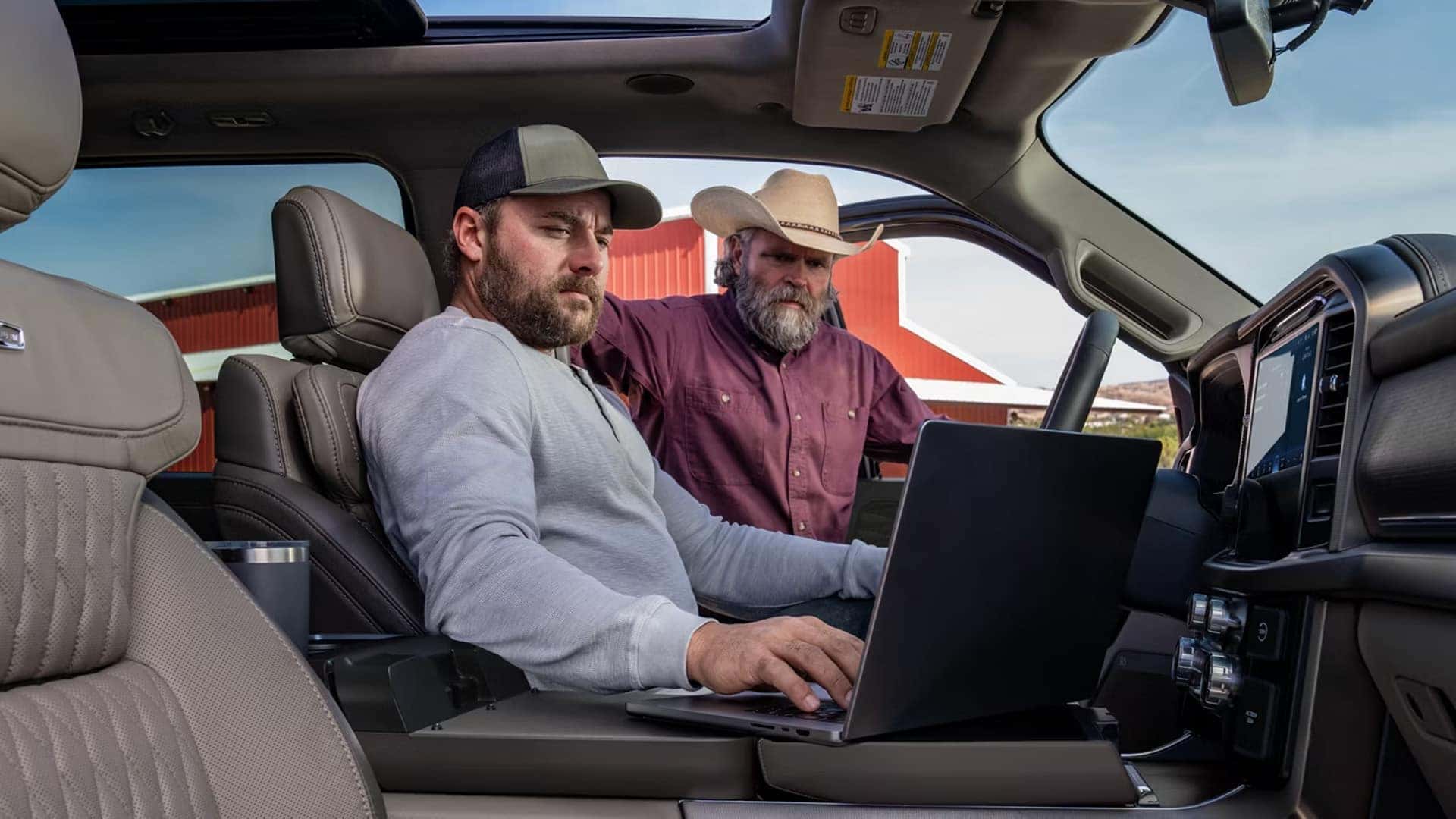 2026 Ford F-150 interior with fold down work surface and laptop in use, highlighting in cabin workspace and productivity features.