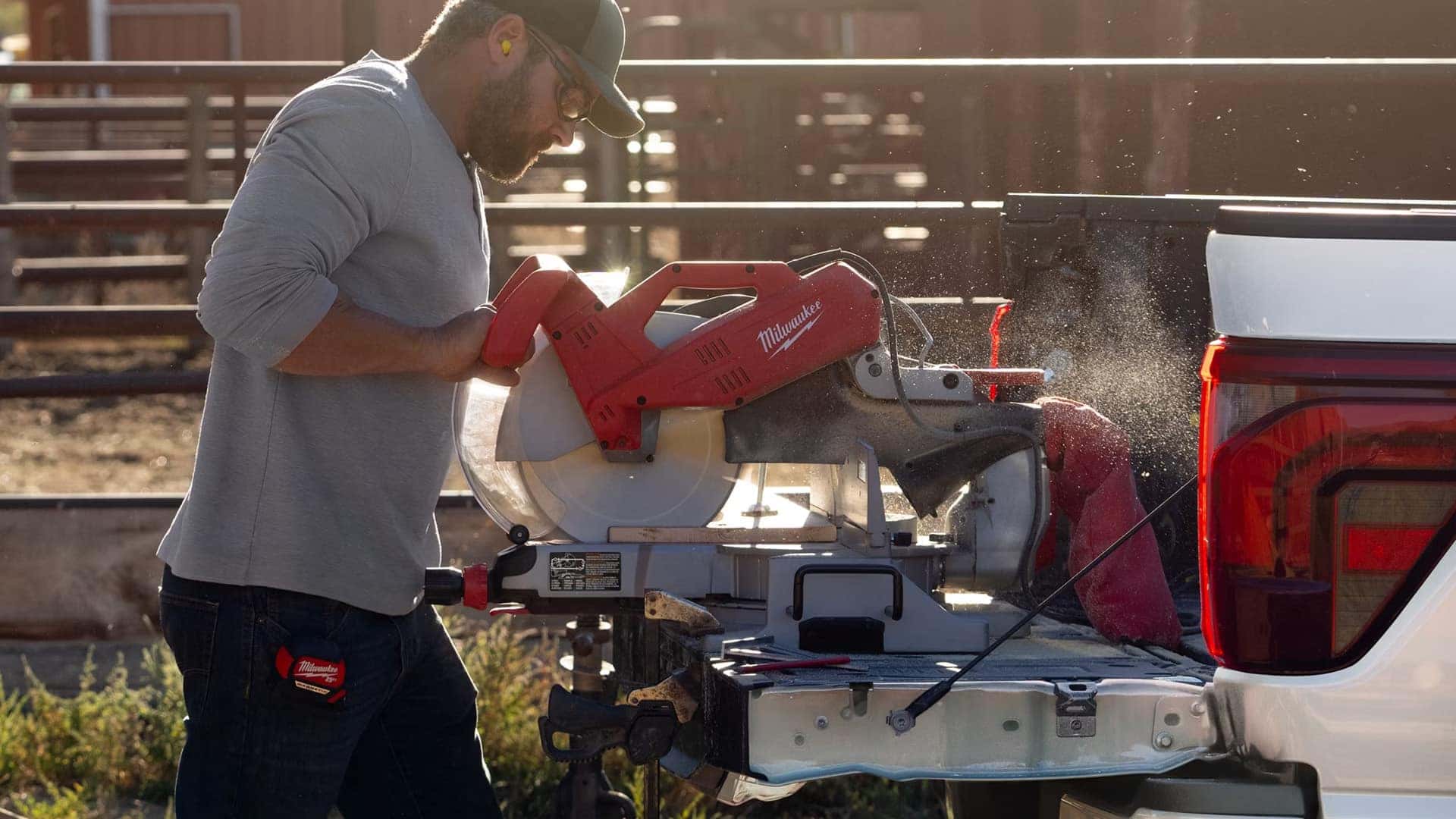 Worker using a power saw on the tailgate of a 2026 Ford F-150, highlighting worksite utility and tailgate support.