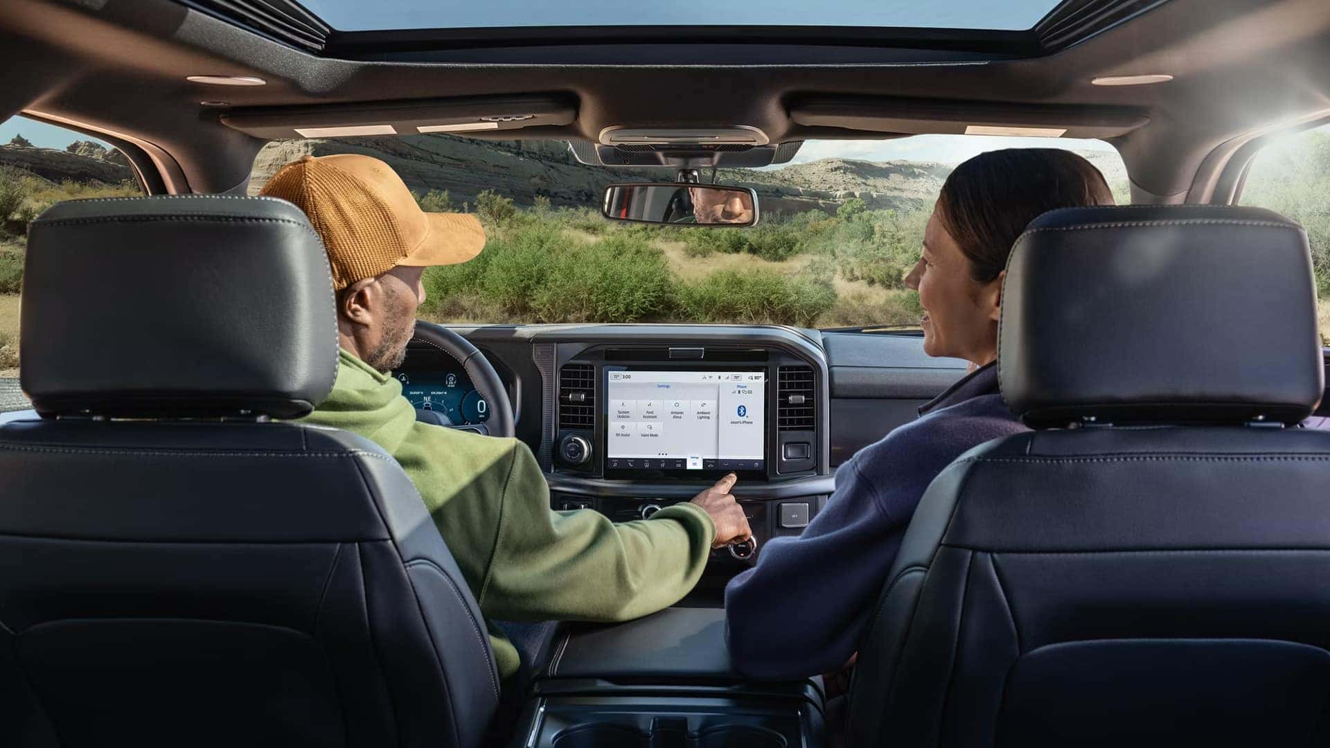 2026 Ford F-150 infotainment and connectivity shown from rear seats with passengers using the center touchscreen on a road trip