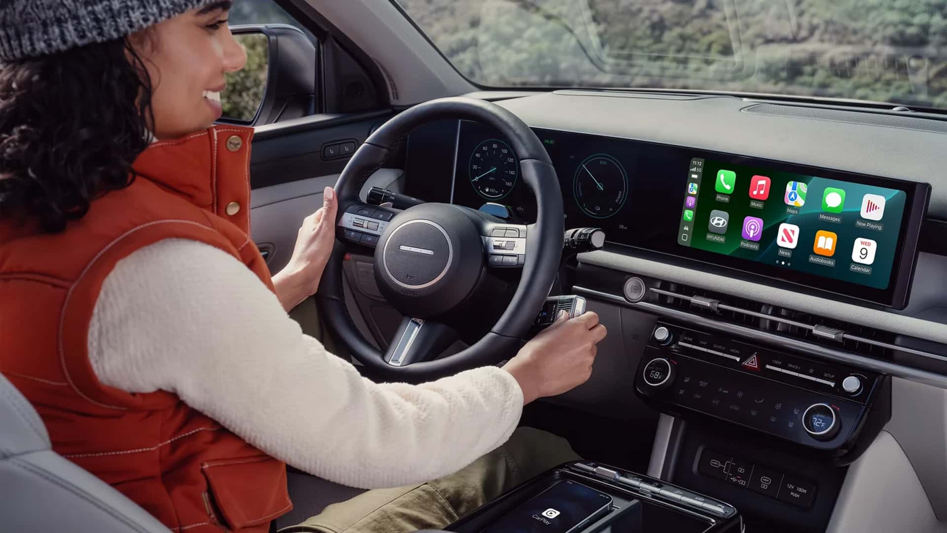 Driver using the Hyundai Tucson Hybrid infotainment system with smartphone connectivity displayed on the touchscreen.