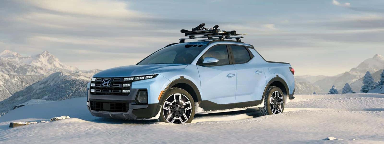 2026 Hyundai Santa Cruz parked in a snowy mountain setting with roof-mounted gear, highlighting compact pickup design and outdoor capability