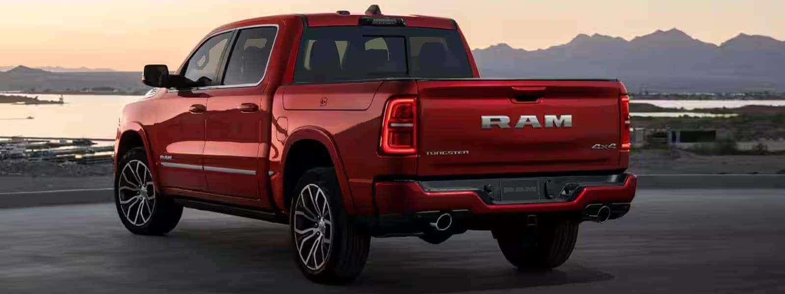 2026 Ram 1500 pickup truck shown from the rear three quarter angle with bold RAM tailgate badging and LED taillights at sunset