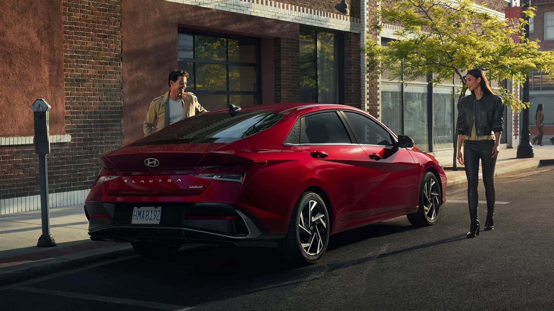 Rear three quarter view of a red 2026 Hyundai Elantra highlighting sculpted body lines, fastback style profile, and exterior design details in an urban setting
