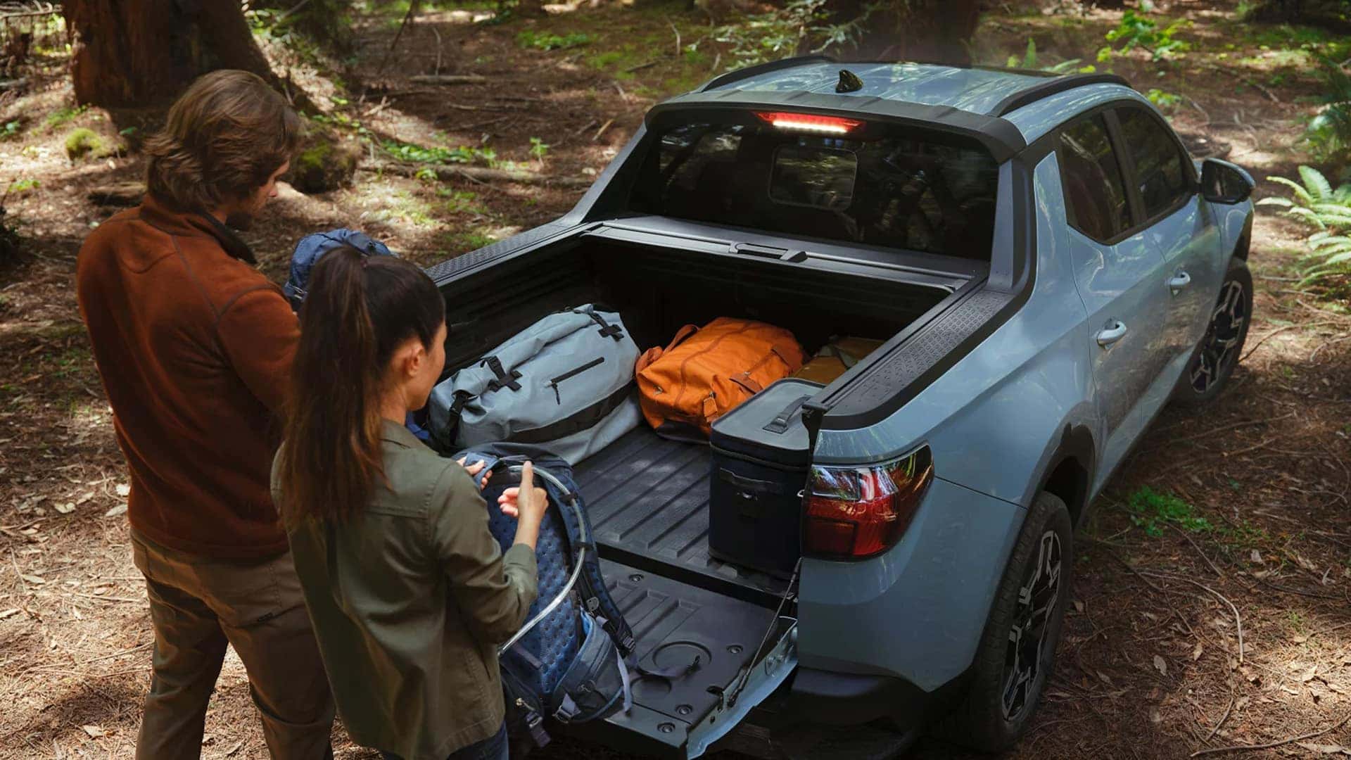 2026 Hyundai Santa Cruz parked in a forest setting with the truck bed open and loaded with camping gear