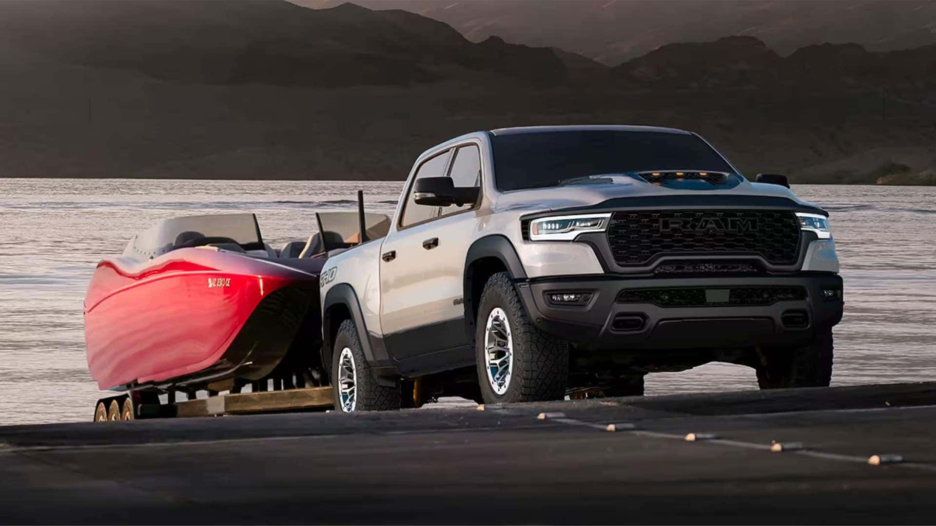 2026 Ram 1500 towing a large recreational boat at a lakeside launch area