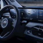 2026 Buick Enclave interior showing steering wheel, wide curved display, and dashboard with ambient lighting controls