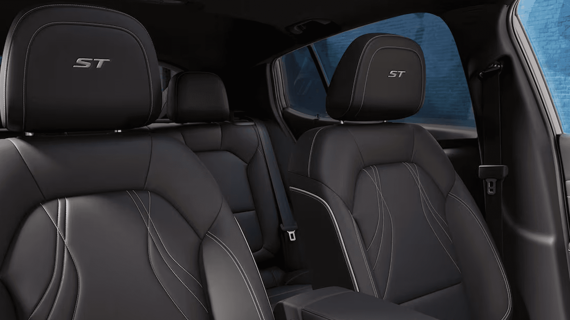 Interior seating view of the 2026 Buick Envista showing black front bucket seats with ST logos and contrast stitching, the rear bench behind them, and the center console extending toward the dashboard