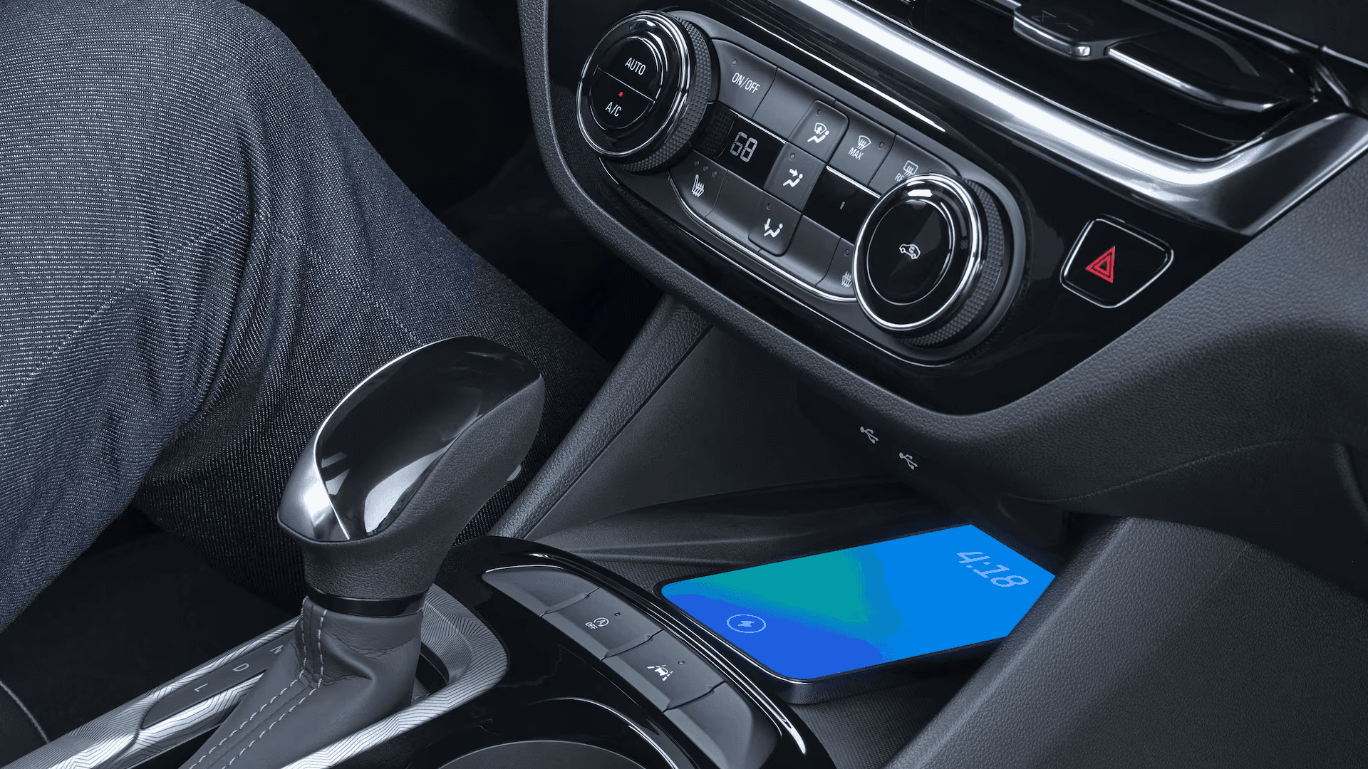 Close-up of the 2026 Buick Envista center console showing the gear shifter, climate controls, and a smartphone resting on the wireless charging pad.