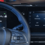 Close-up of the driver area showing the Buick steering wheel, digital instrument cluster, and center touchscreen with menu icons like Android Auto, Apple CarPlay, and Wi-Fi Hotspot.
