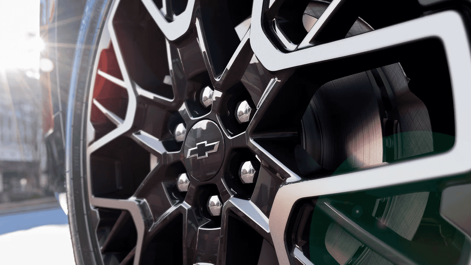 Close up of a Chevy Blazer aluminum wheel showing the multi spoke design, lug nuts, brake rotor, and Chevrolet bowtie center cap.