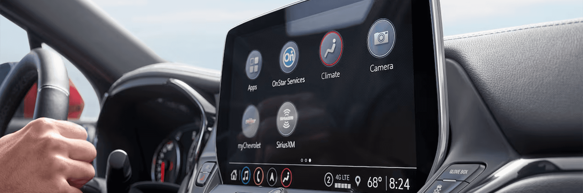 Close up of the Chevy Blazer infotainment touchscreen showing icons for Apps, OnStar Services, Climate, Camera, myChevrolet, and SiriusXM, with the steering wheel and gauge cluster in the background.