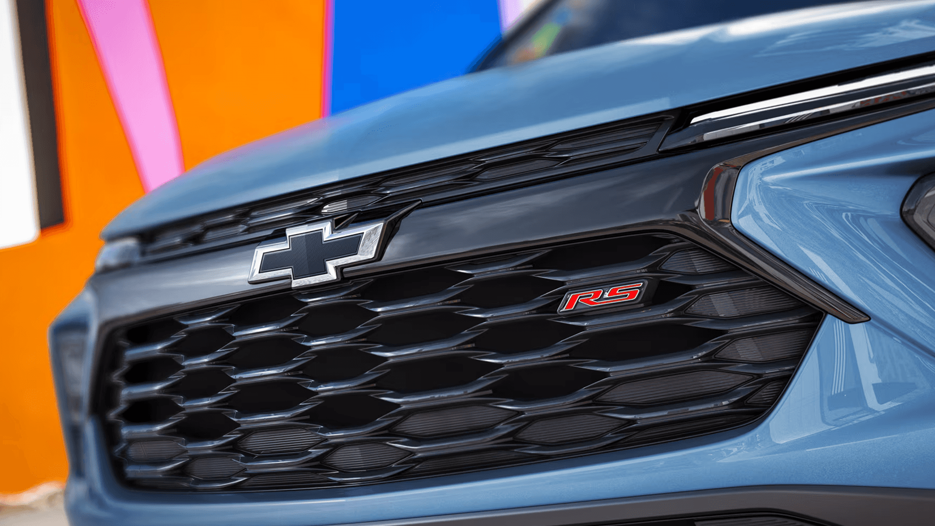 Close up of the front grille on a blue Chevy Trailblazer RS showing the black honeycomb pattern and red RS badge.