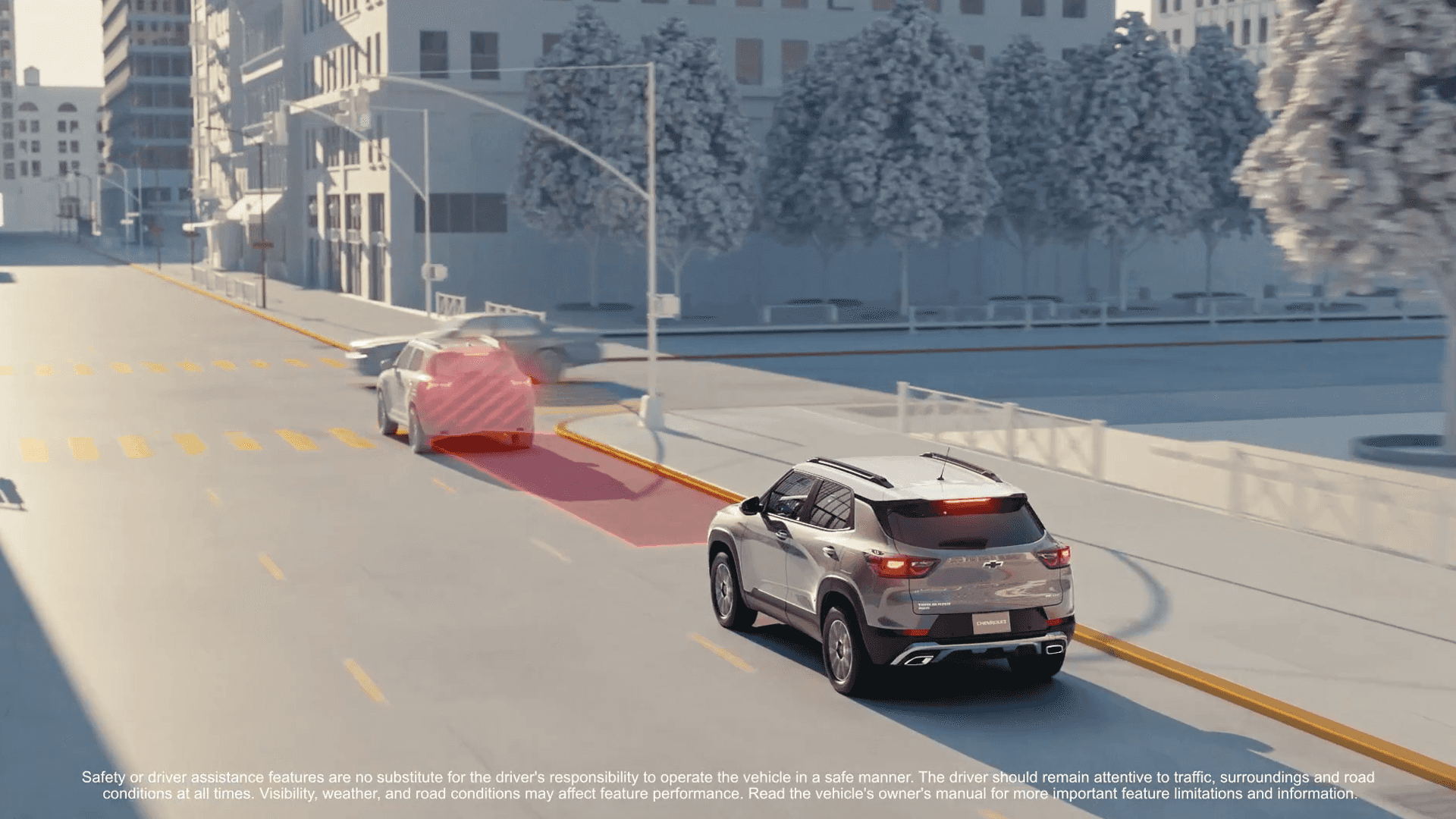 Driver-assistance demonstration graphic showing a Chevrolet Trailblazer on a city street with a red highlighted zone behind a vehicle ahead, illustrating a safety alert or automated braking scenario, with simplified buildings, trees, lane markings, and small safety disclaimer text along the bottom.