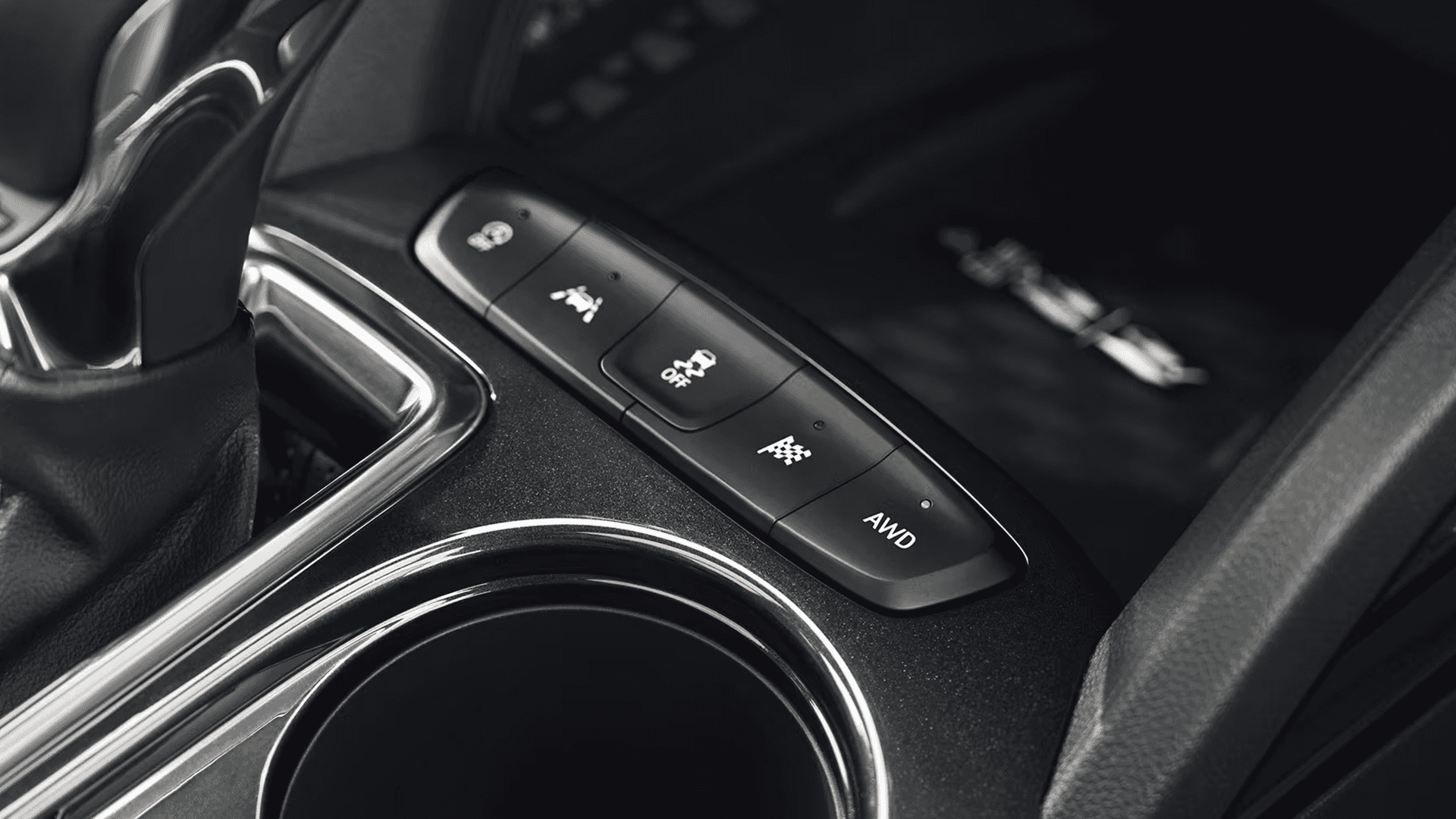 Close-up of center console buttons showing AWD, traction control, and drive mode switches beside cupholder.