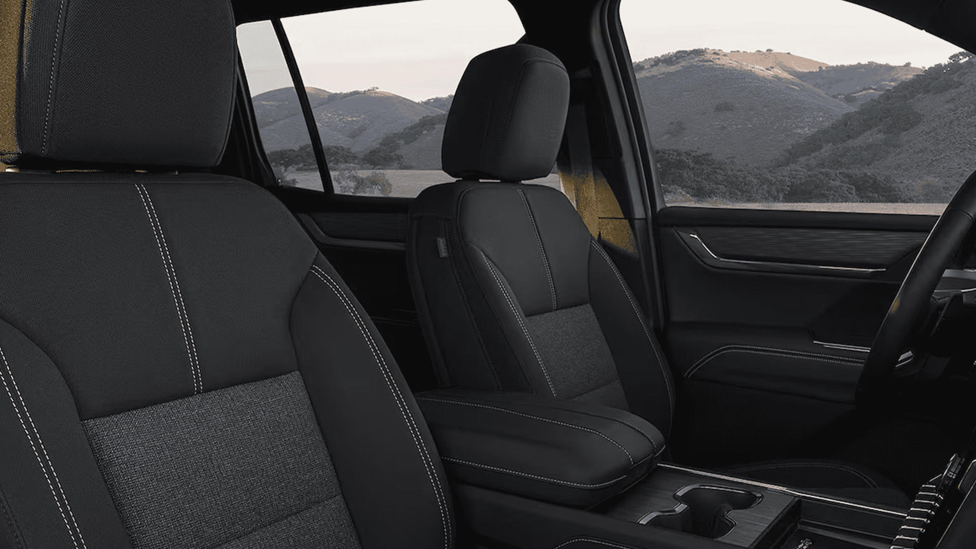 Driver cockpit view of the 2026 GMC Acadia Denali showing the steering wheel, digital displays, and large vertical touchscreen in the center stack