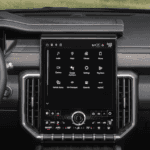 Wide cabin view of the 2026 GMC Acadia interior showing the Denali steering wheel, digital driver display, and large portrait center touchscreen framed by vertical vents.