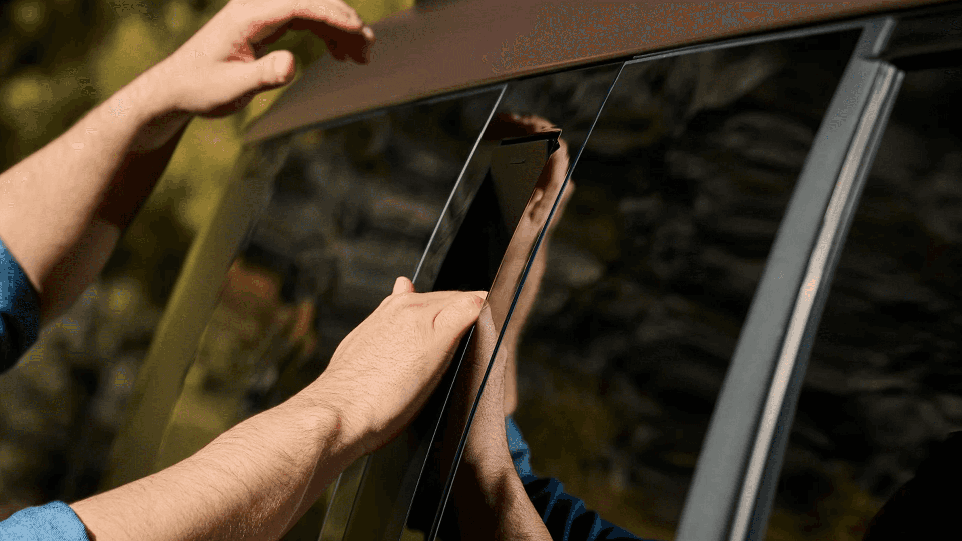 Close up of hands pulling out the hidden side assist handle on the Santa Fe near the rear side window, showing the concealed roof access grip integrated into the exterior trim.