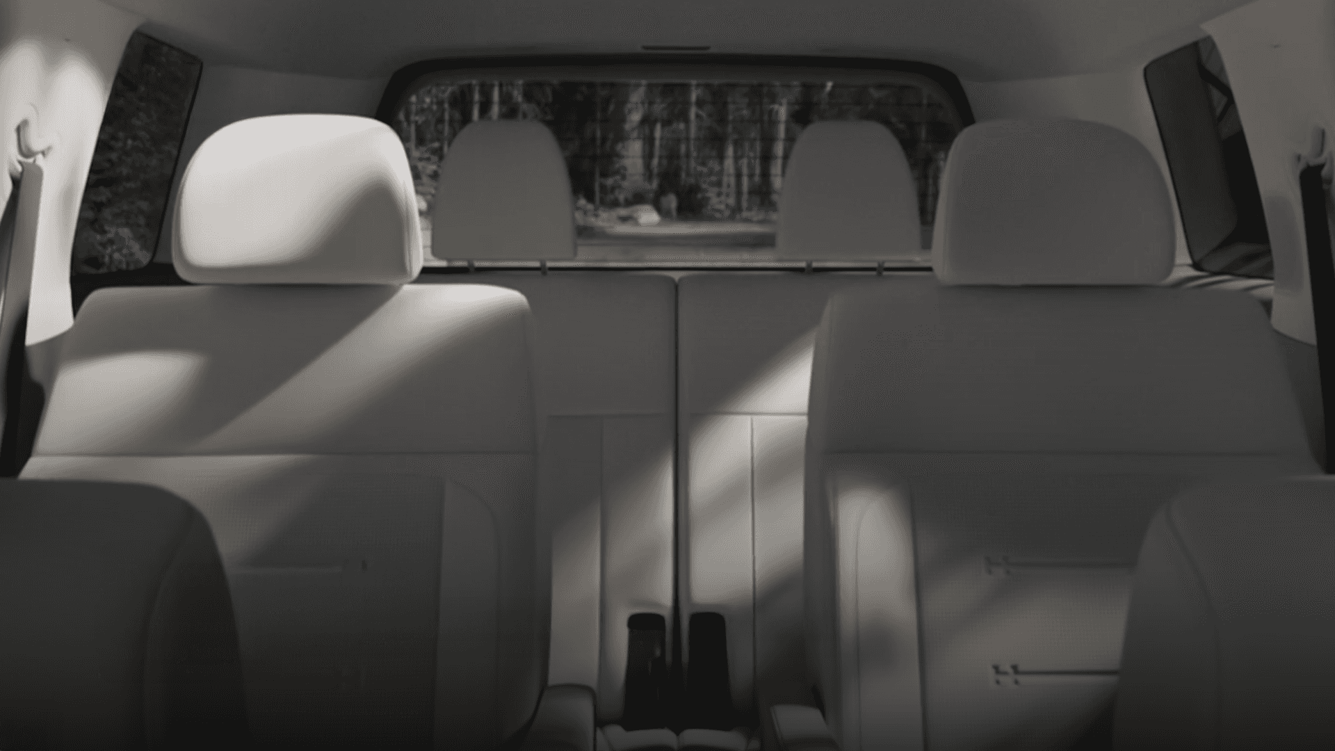 View from the front seats looking toward the rear of the 2026 Hyundai Santa Fe Hybrid showing the second row seatbacks, headrests across the cabin, rear side windows, and natural light casting shadows across the upholstery.