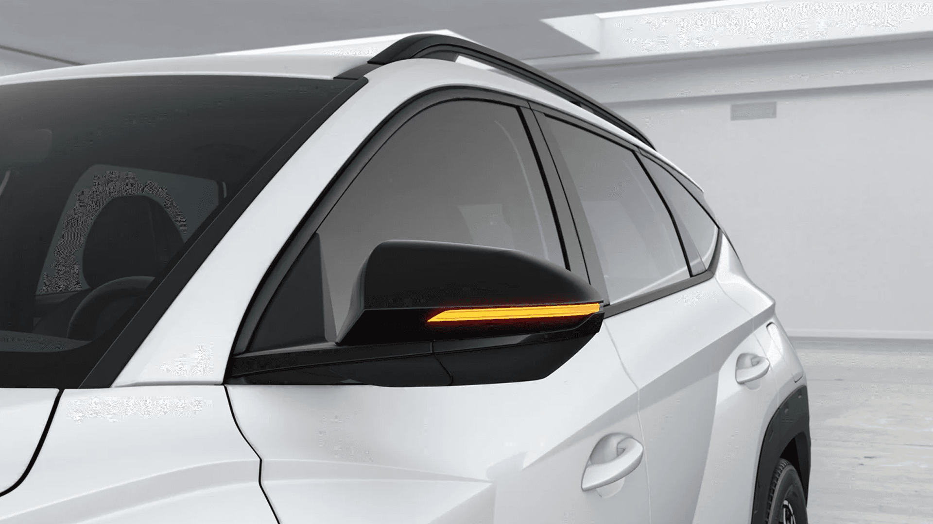 Close-up studio view of a white 2026 Hyundai Tucson showing the roof side rails and side mirror with the amber turn signal indicator lit, plus tinted side windows and door handles.