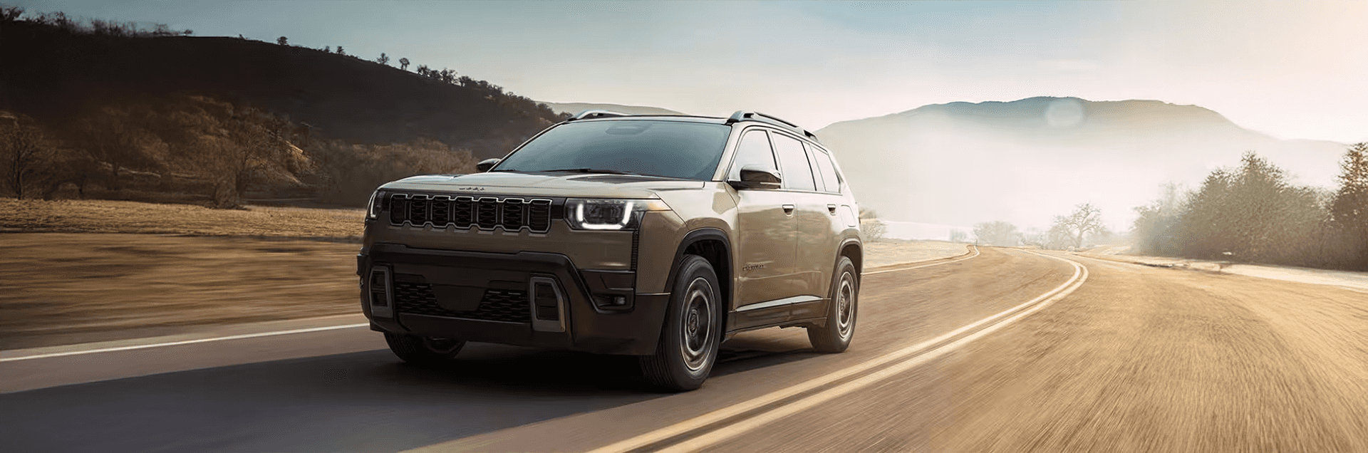 2026 Jeep Cherokee driving on a paved road with front three quarter view in daylight