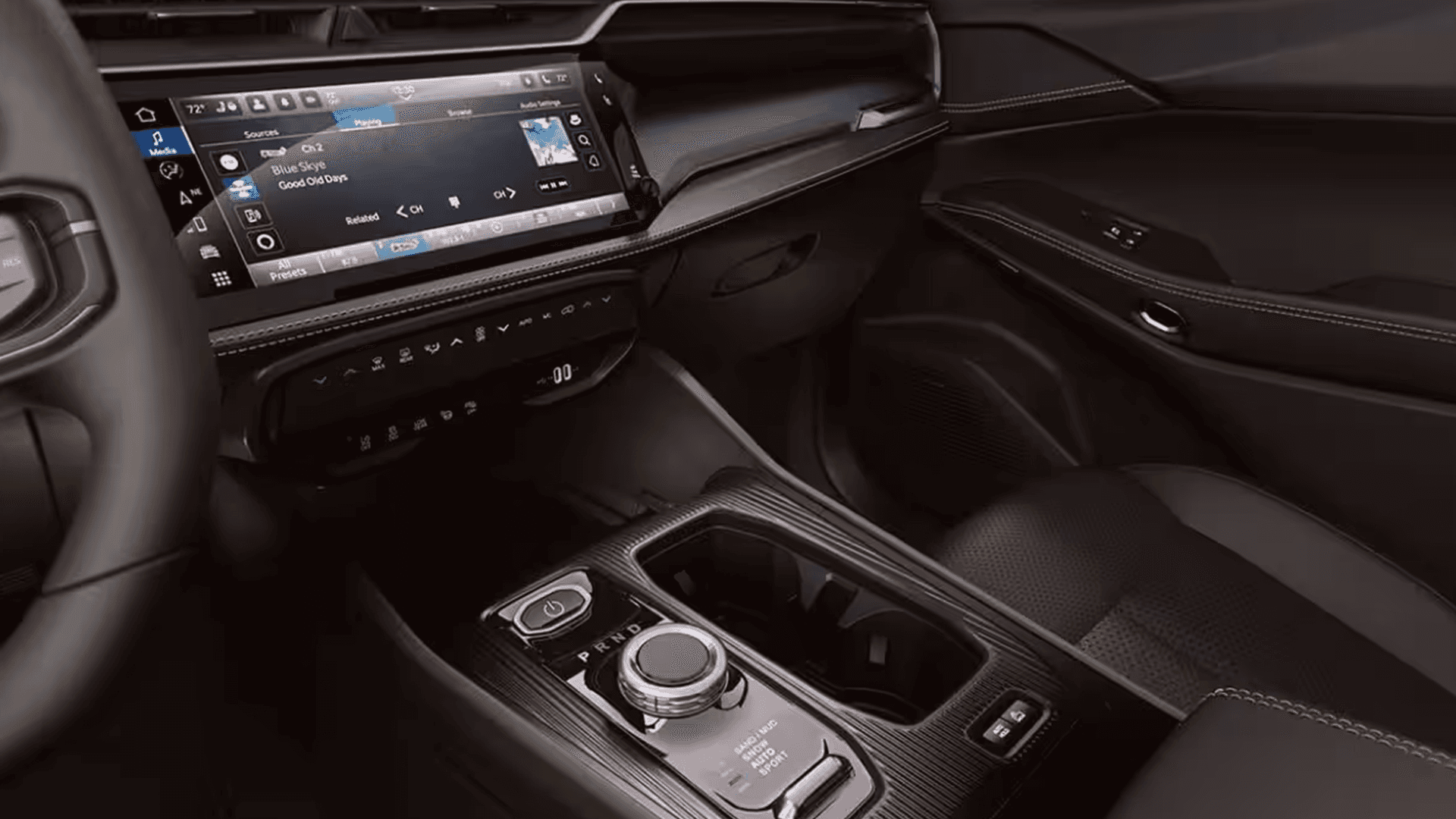 Front passenger side interior closeup of the 2026 Jeep Cherokee showing the center touchscreen, climate controls, rotary gear selector, cupholders, and contrast stitching on the dash and door panel.