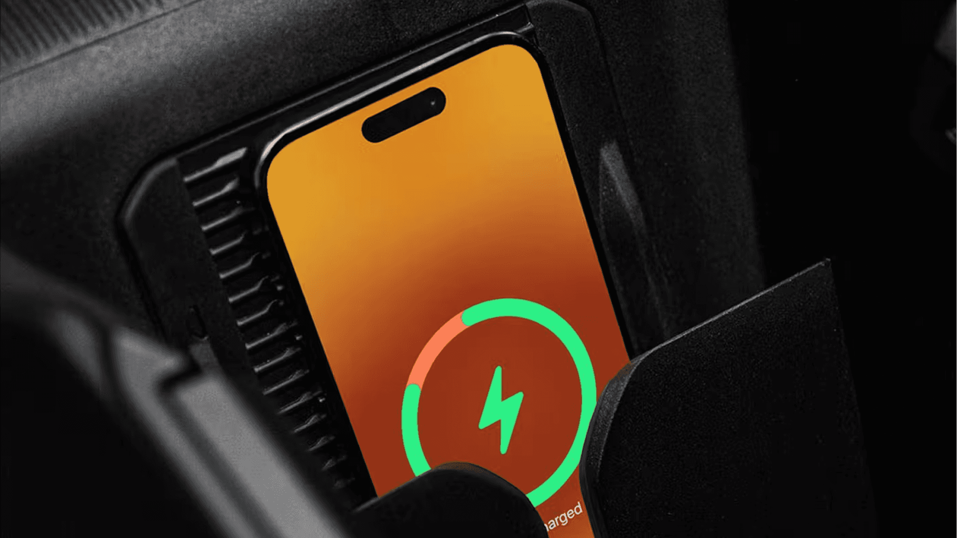 Close up of a smartphone resting on an in vehicle wireless charging pad, with a large green charging ring and lightning icon on the screen.