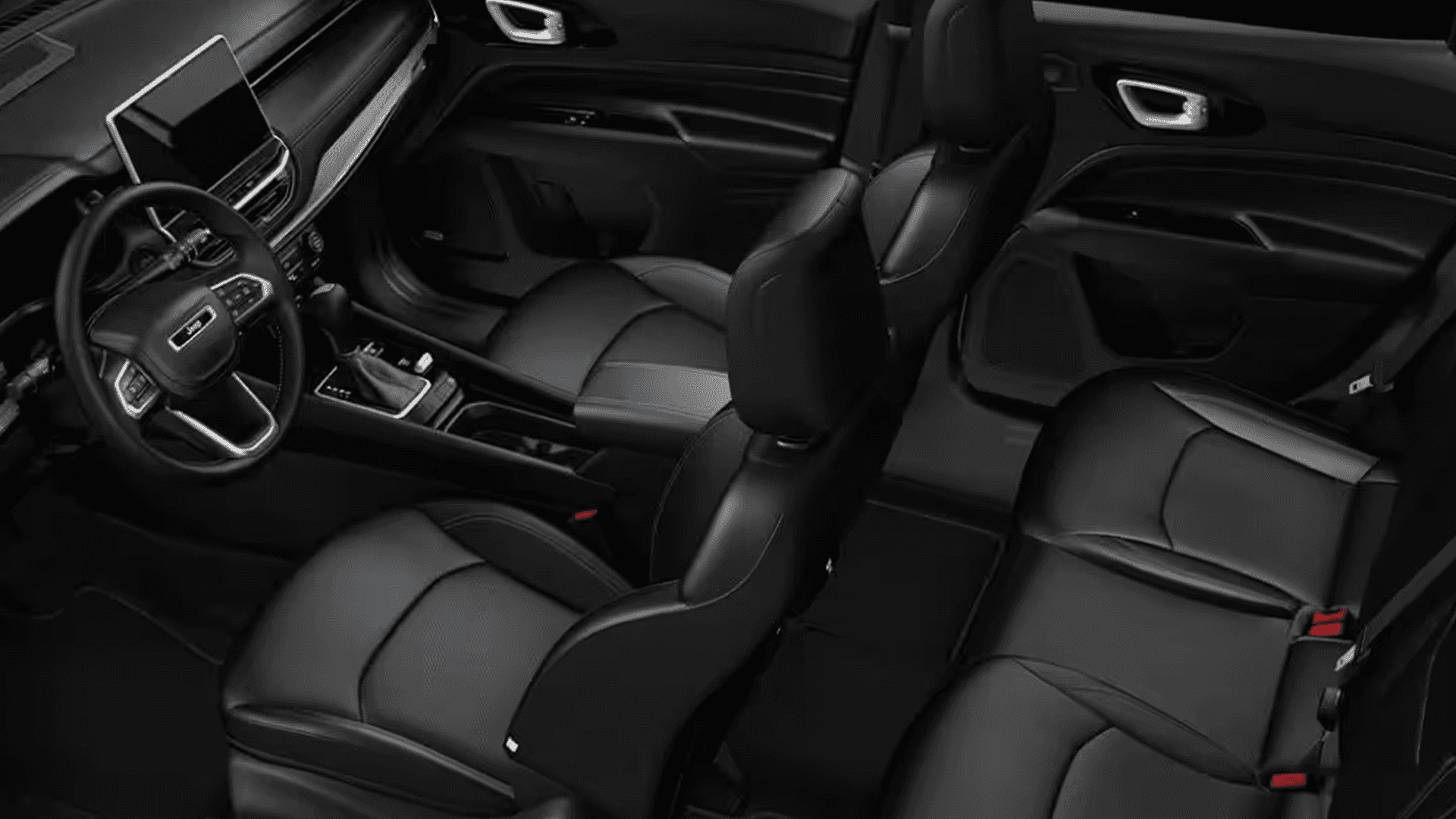 Jeep Compass interior showing front seats, steering wheel, center console, and dashboard screen in a black cabin.