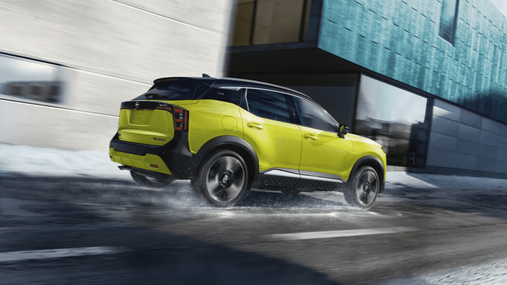 Lime green 2026 Nissan Kicks driving on a wet road with water spray behind the tires, shown from a rear three quarter angle near modern buildings, highlighting its ground clearance and sporty stance