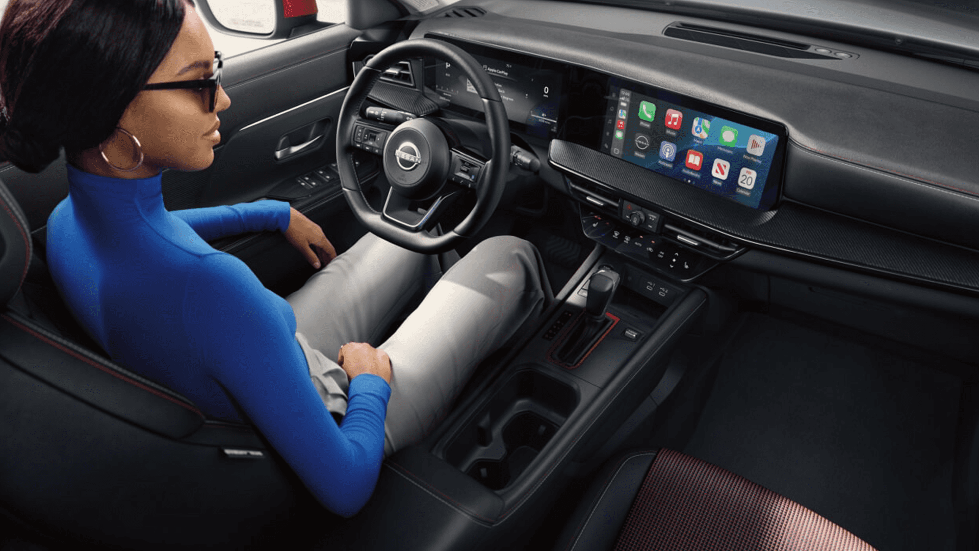 Driver in the 2026 Nissan Kicks viewing the wide infotainment display with Apple CarPlay apps