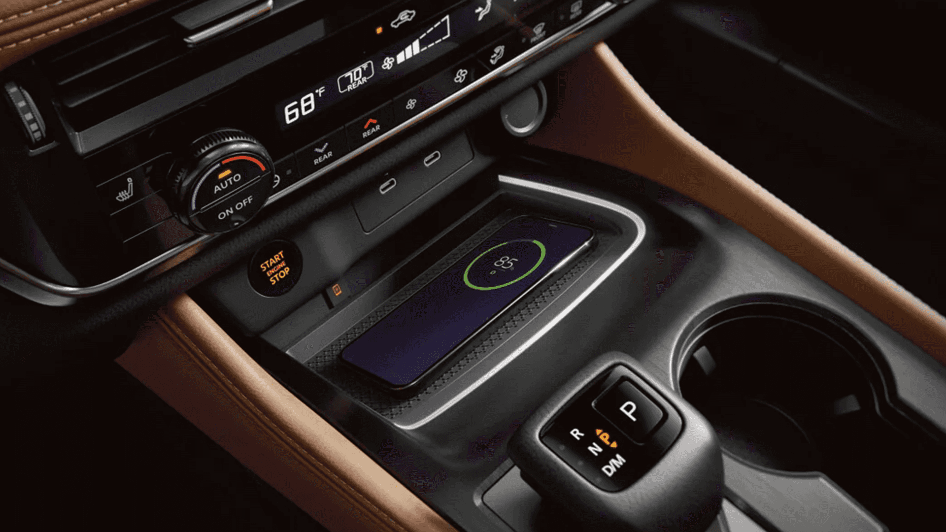 Smartphone charging on the wireless charging pad beside the shifter and climate controls in a Nissan interior