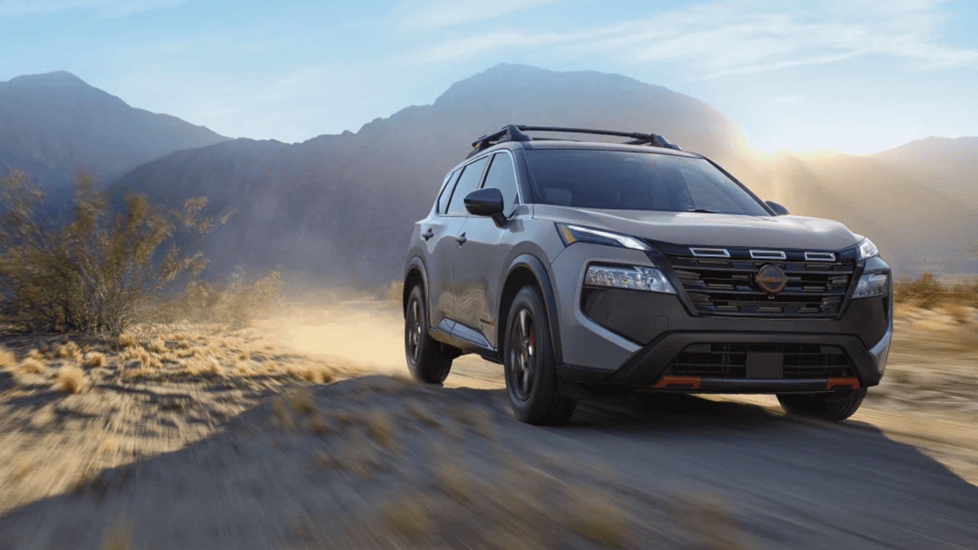 2026 Nissan Rogue driving on a dirt road showcasing available Intelligent All Wheel Drive capability