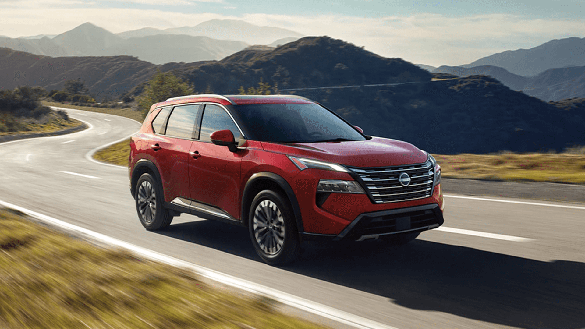2026 Nissan Rogue driving on a winding road highlighting exterior design and front styling