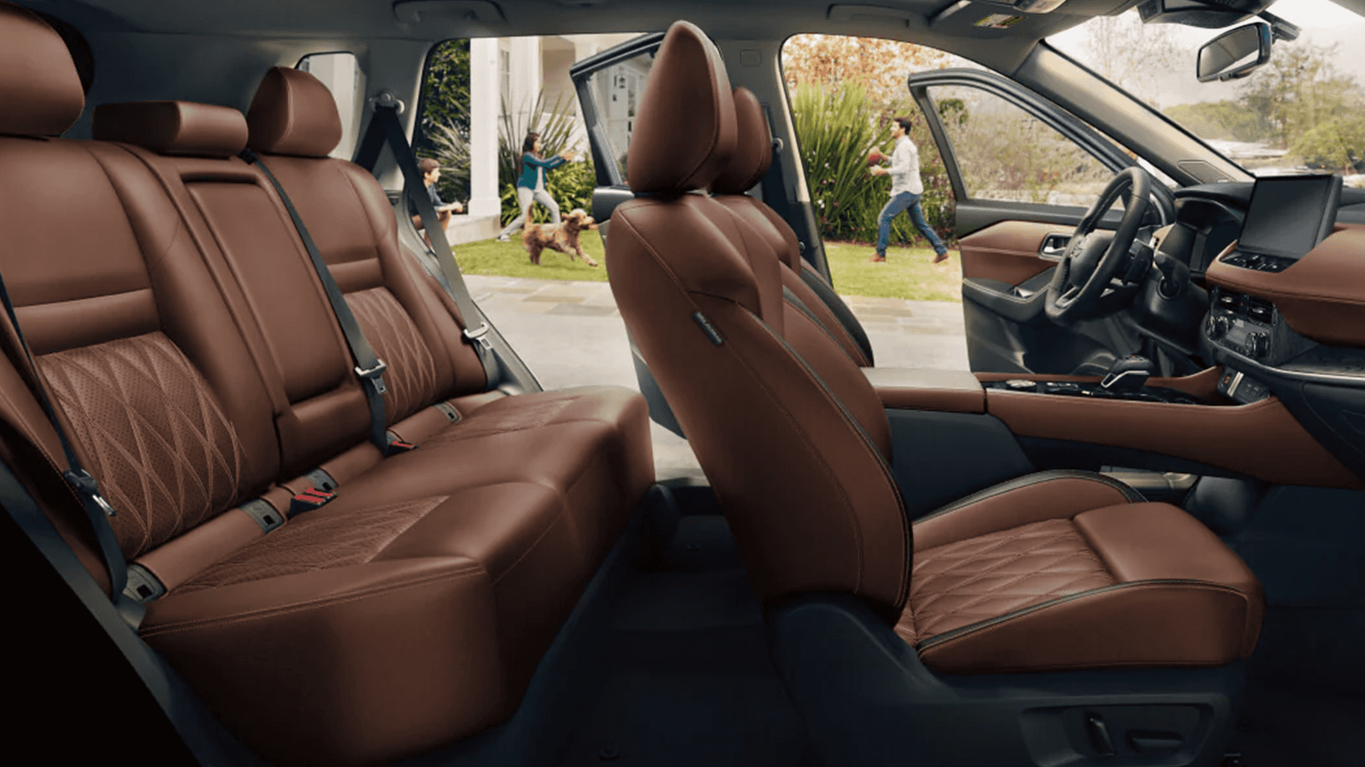 View through open passenger doors showing brown leather front and rear seats and the Rogue dashboard