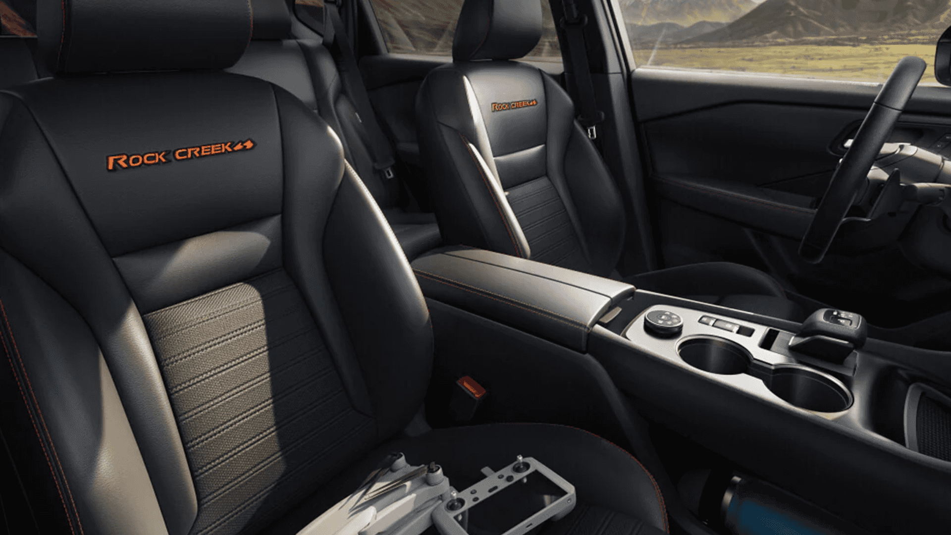 2026 Nissan Rogue front seats and center console with cup holders and orange stitching accents