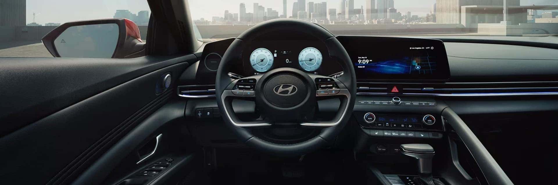 Interior view of the 2026 Hyundai Elantra showing the steering wheel, digital instrument cluster, wide touchscreen display, and center console technology features.